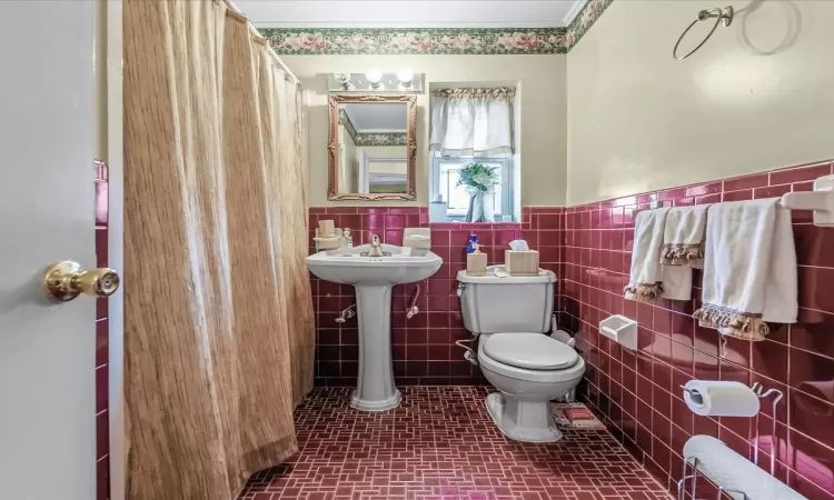 Bathroom with toilet, tile walls, and wainscoting