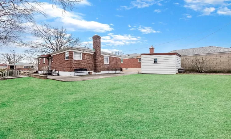 View of yard featuring a patio, an outdoor structure, and a storage unit