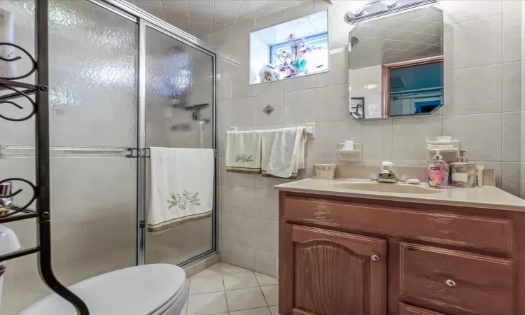 Bathroom with a stall shower, tile walls, and vanity