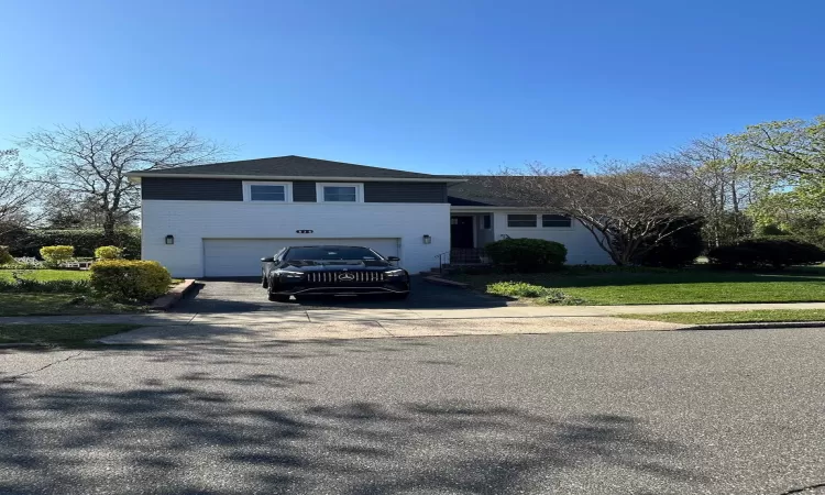 Split level home featuring a garage, brick siding, and driveway