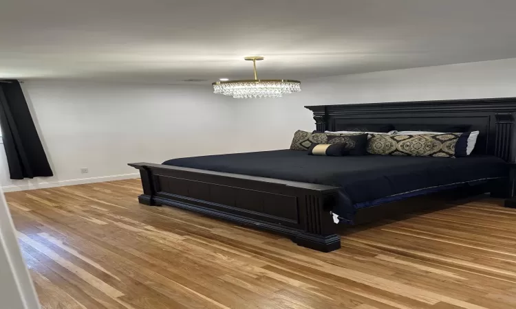 Bedroom with visible vents, baseboards, and wood finished floors