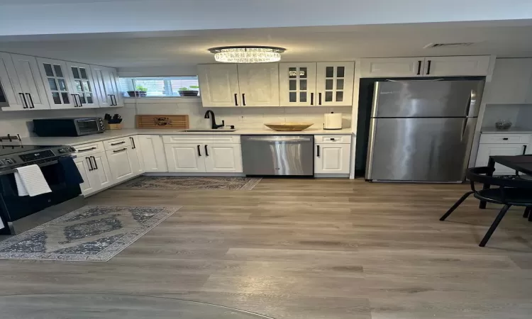 Kitchen featuring a sink, visible vents, light countertops, appliances with stainless steel finishes, and decorative backsplash