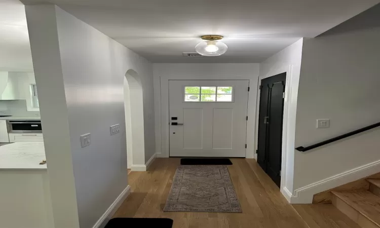 Doorway to outside with stairs, baseboards, arched walkways, and wood finished floors