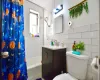 Bathroom with toilet, vanity, tile walls, and shower / tub combo with curtain