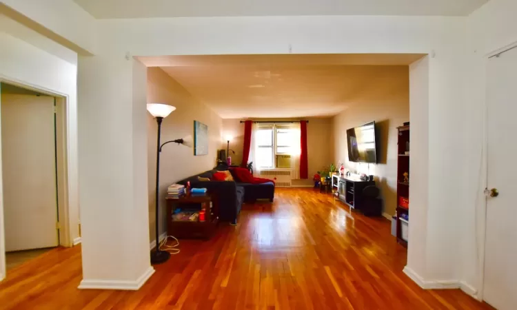 Corridor with radiator, baseboards, and wood finished floors