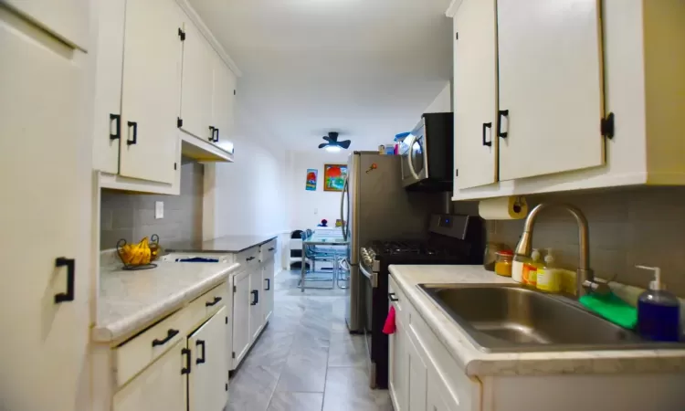 Kitchen featuring stainless steel appliances, a sink, light countertops, and white cabinets