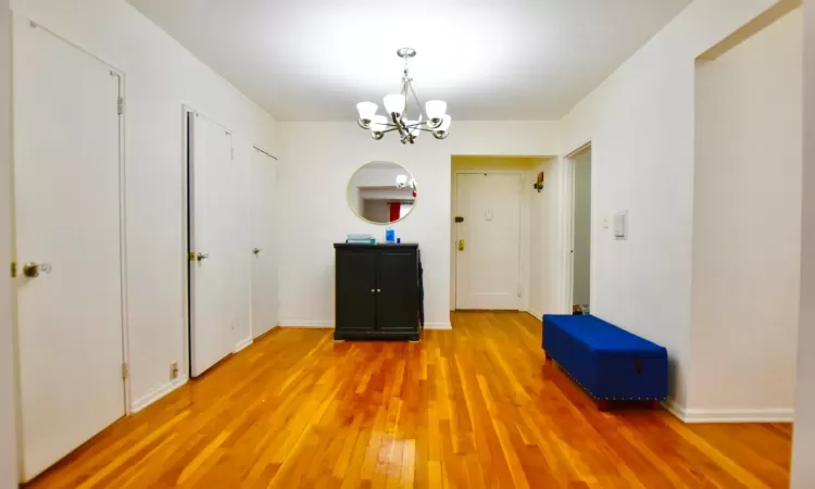 Unfurnished dining area featuring light wood-type flooring, baseboards, and a notable chandelier