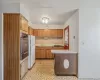 Kitchen featuring freestanding refrigerator, light countertops, stainless steel oven, backsplash, and a warming drawer