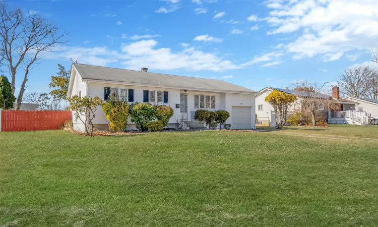 Ranch-style house with a garage, fence, a chimney, and a front lawn