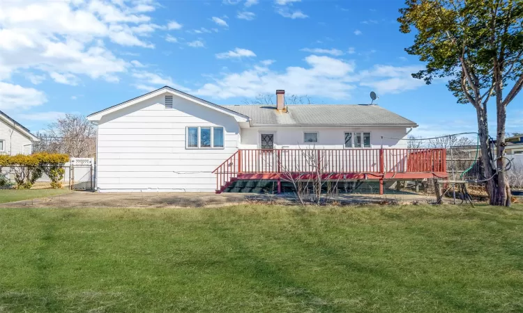 Rear view of property with a lawn, a deck, and fence