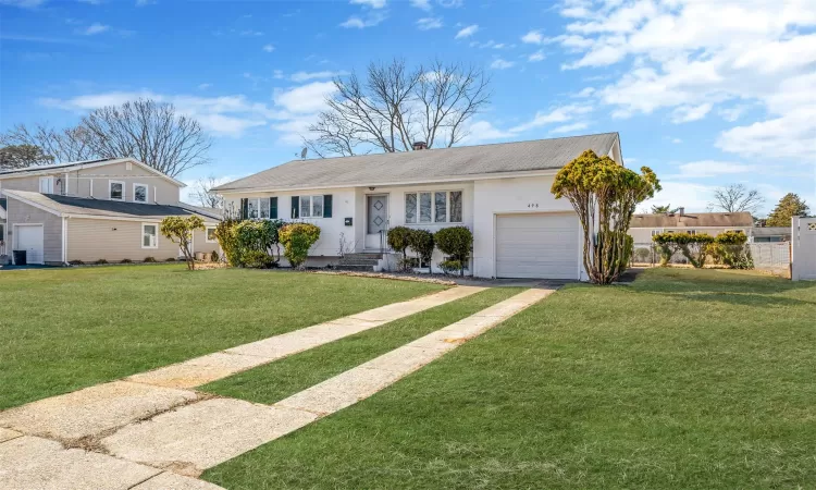 View of front of house featuring entry steps, an attached garage, driveway, a chimney, and a front yard