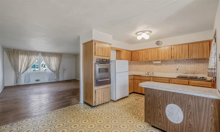 Kitchen with a sink, stainless steel oven, freestanding refrigerator, a warming drawer, and tasteful backsplash