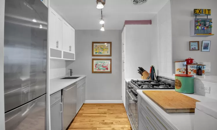 Kitchen featuring visible vents, a sink, light countertops, light wood-style floors, and appliances with stainless steel finishes