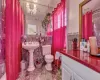 Bathroom with a chandelier, a wainscoted wall, tile walls, and toilet