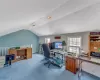 Carpeted home office with lofted ceiling, visible vents, and baseboards