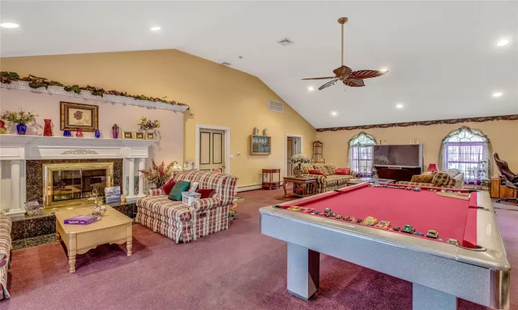 Playroom with visible vents, ceiling fan, carpet flooring, high vaulted ceiling, and a high end fireplace