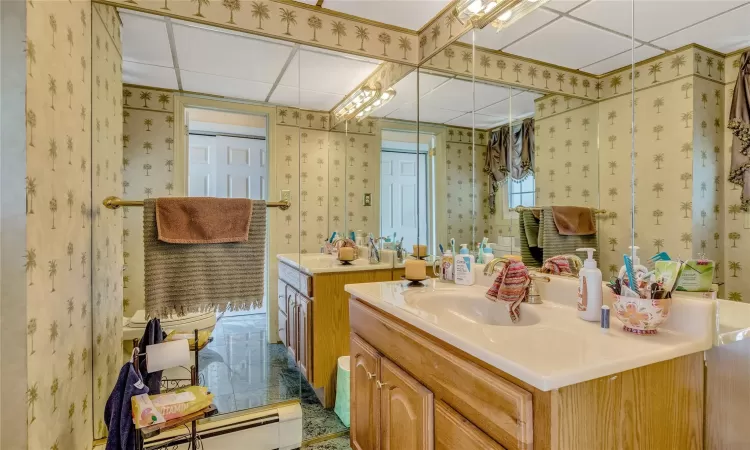 Bathroom featuring wallpapered walls, a baseboard radiator, and vanity