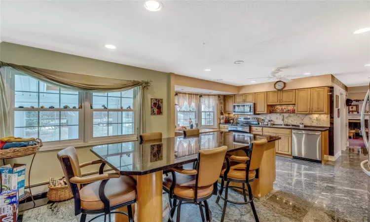 Kitchen featuring stainless steel appliances, dark countertops, a kitchen island, and a kitchen breakfast bar