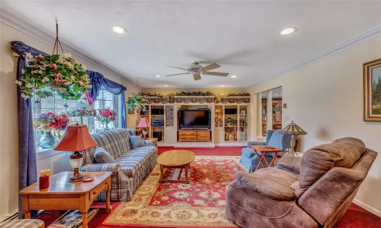 Carpeted living room featuring ceiling fan, recessed lighting, and crown molding