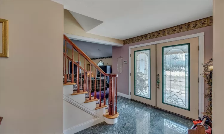 Foyer featuring marble finish floor, baseboards, stairway, and french doors