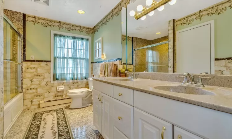 Full bathroom featuring toilet, a baseboard radiator, a sink, and tile walls