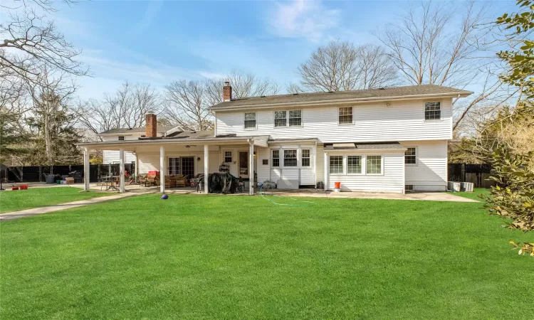 Back of house featuring a patio area, a chimney, fence, and a yard