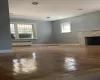 Unfurnished living room featuring a premium fireplace, baseboards, radiator, and wood finished floors