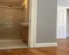 Bathroom featuring baseboards, wood finished floors, a stall shower, and vanity