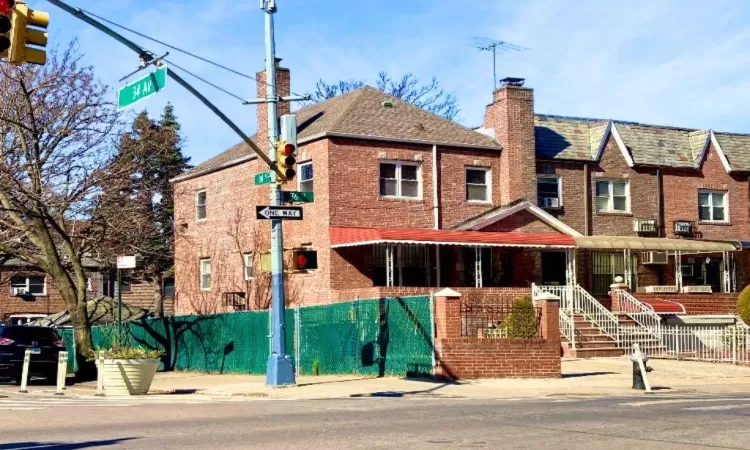 View of front facade featuring fence, brick siding, and a chimney