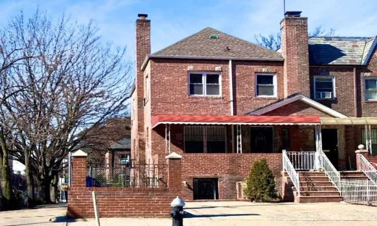 View of front of property with a porch, brick siding, and a chimney