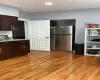 Kitchen with dark brown cabinets, light wood-style flooring, and freestanding refrigerator