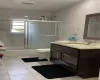 Bathroom featuring visible vents, toilet, vanity, combined bath / shower with glass door, and tile walls