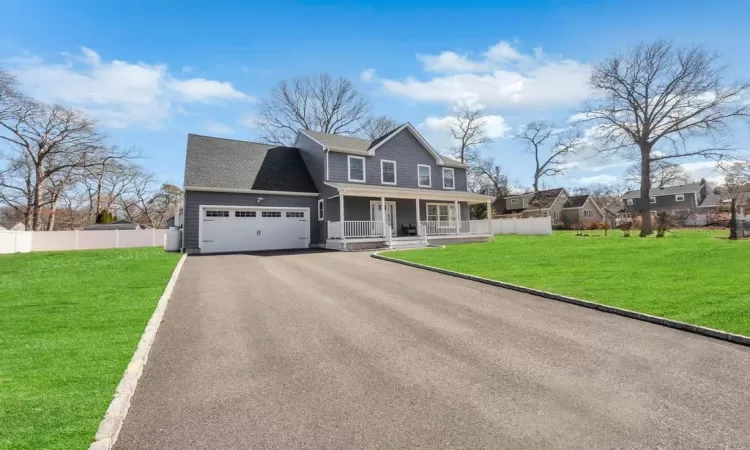 View of front of property with a front lawn, fence, aphalt driveway, covered porch, and an attached garage