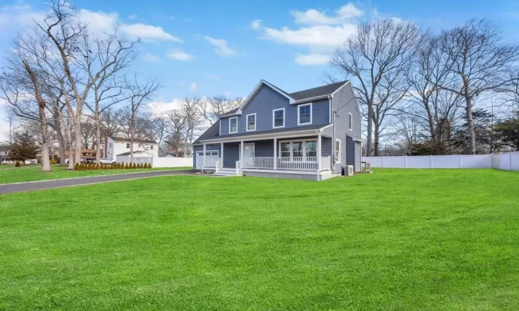 View of front of house with a front lawn, driveway, fence, covered porch, and an attached garage