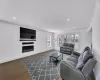 Living area featuring baseboards, dark wood-type flooring, a glass covered fireplace, and crown molding