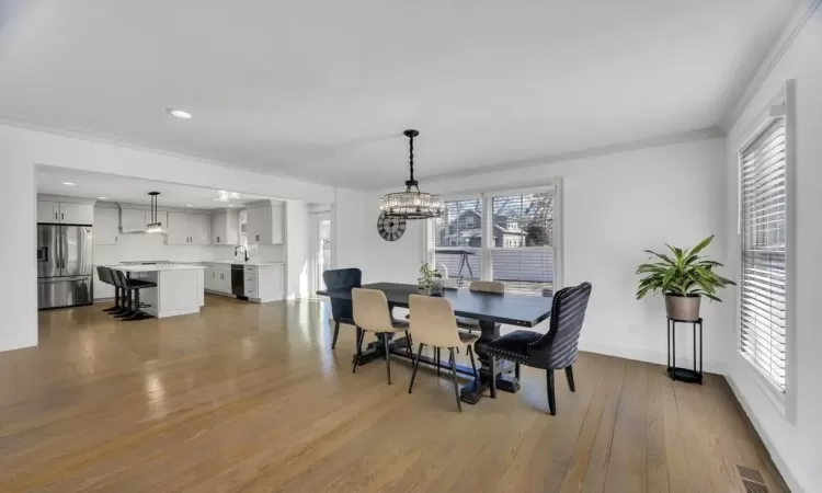 Living room with stairway, wood finished floors, baseboards, recessed lighting, and crown molding