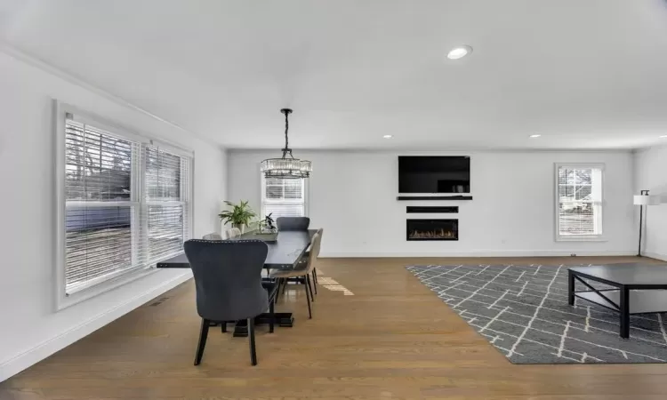 Dining area featuring an inviting chandelier, wood-type flooring, baseboards, and ornamental molding