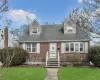 Cape cod home featuring a front yard, brick siding, and roof with shingles