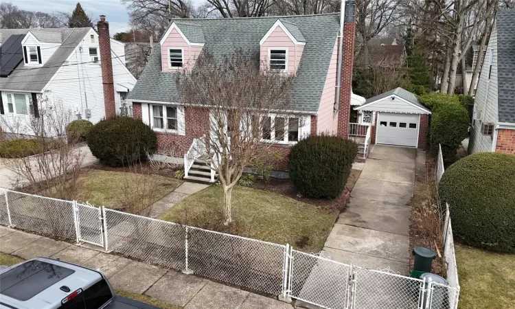 New england style home featuring a shingled roof, a gate, and a chimney