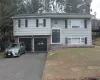 Raised Ranch with aphalt driveway, brick siding, a chimney, an attached garage, and a front yard