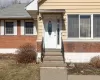 View of front of property with brick siding, a shingled roof, a front yard, fence, and a garage