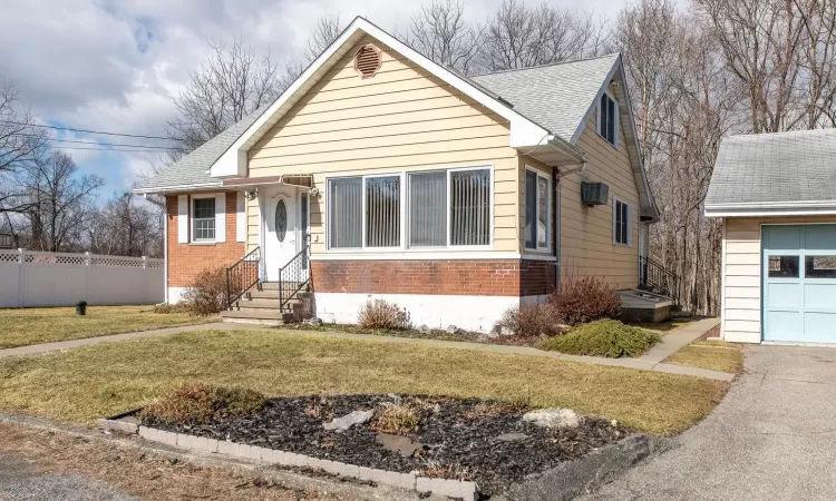 View of front of property with a front lawn, entry steps, brick siding, and an attached garage