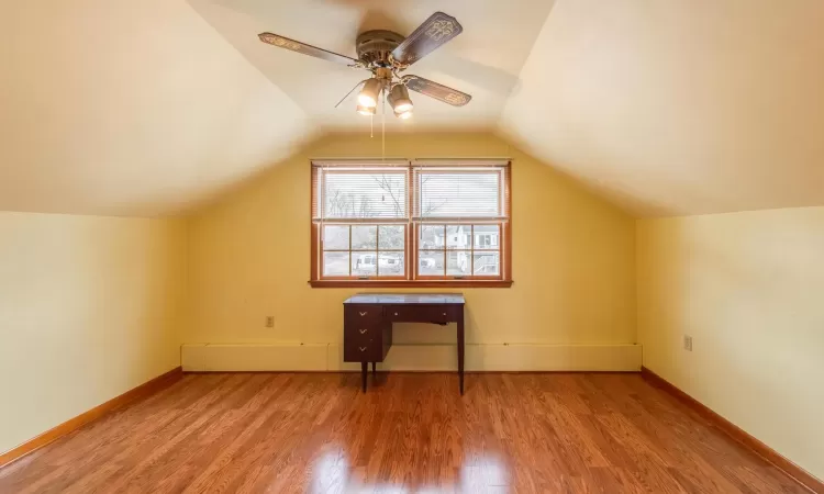 Carpeted bedroom with a ceiling fan, lofted ceiling, and baseboards