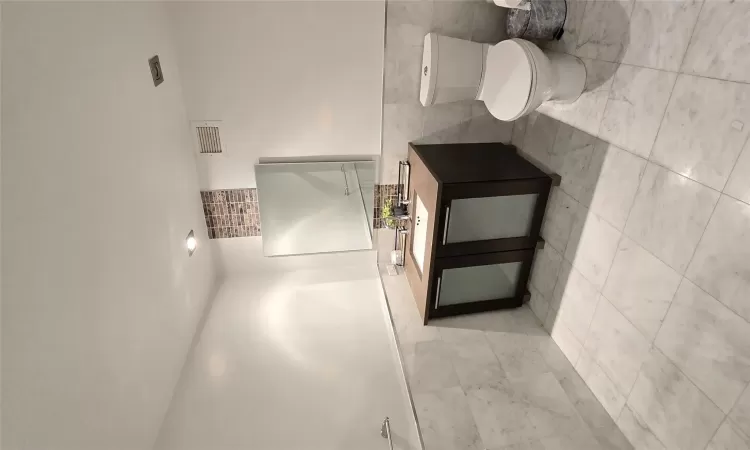 Bathroom with wainscoting, visible vents, and tile walls