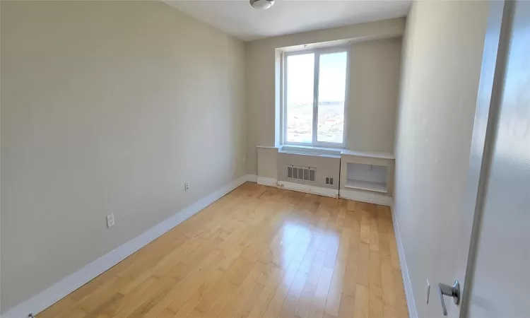 Spare room with light wood finished floors, baseboards, and visible vents