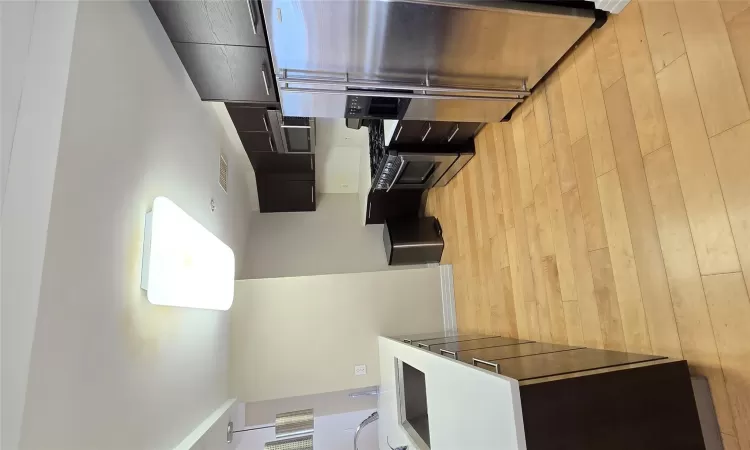 Kitchen with light wood finished floors, visible vents, range, fridge, and a sink