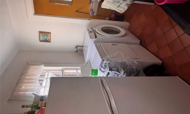 Clothes washing area featuring tile patterned flooring, laundry area, and washing machine and dryer