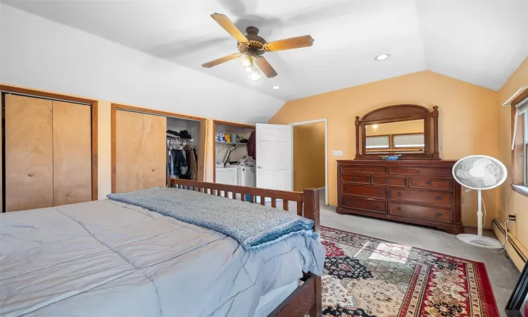 Bedroom featuring washer and clothes dryer, carpet flooring, two closets, and vaulted ceiling