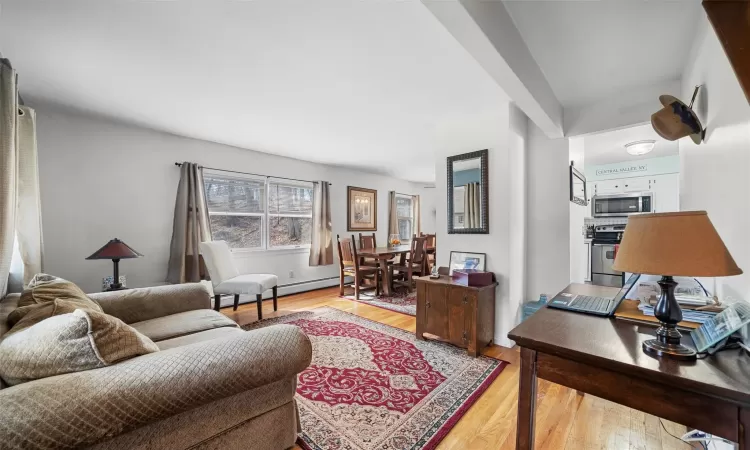 Living area with a baseboard heating unit and light wood finished floors