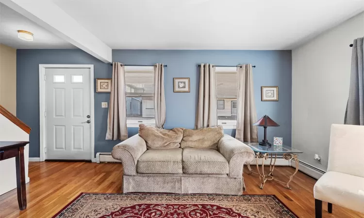 Living room with a baseboard heating unit, baseboards, and light wood-style floors